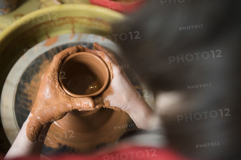 Caucasian woman shaping pottery clay on wheel