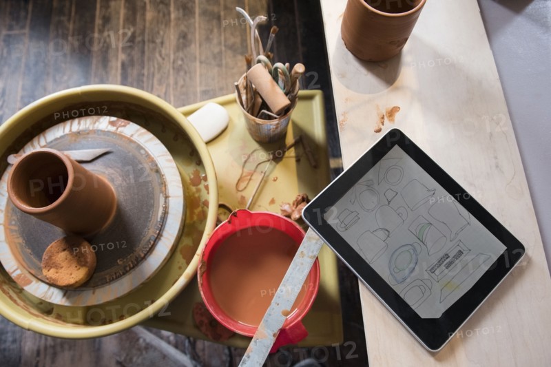 Cup and tools on pottery wheel near digital tablet