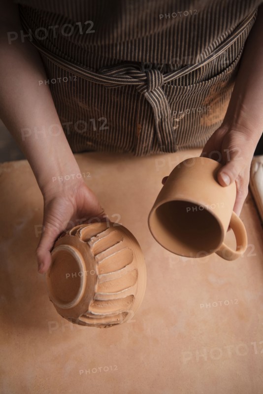 Hand of Caucasian woman holding pottery cup and bowl