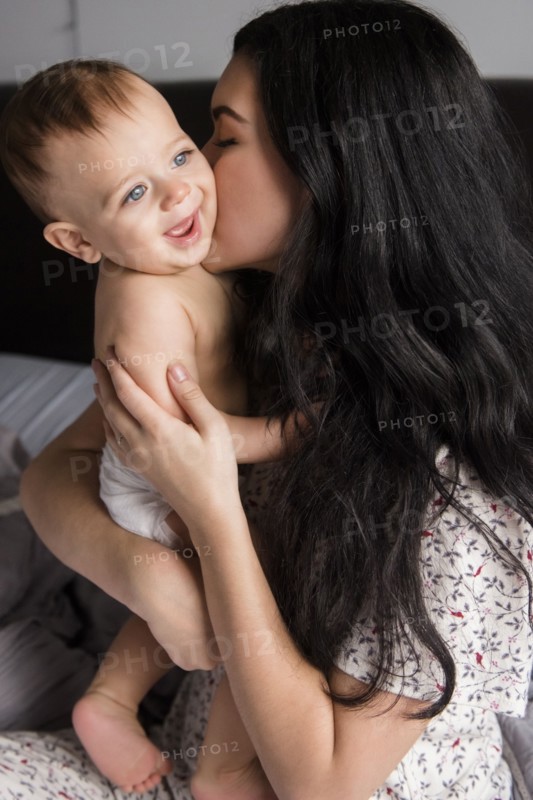 Caucasian mother kissing baby son in bed