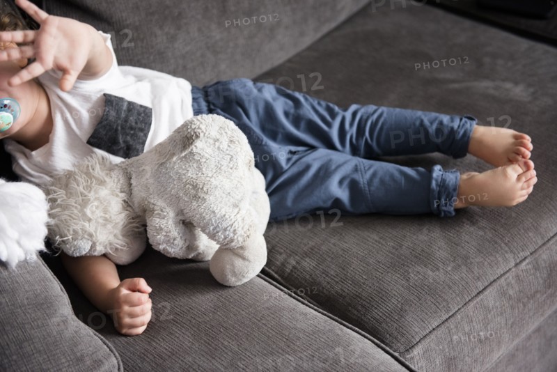 Caucasian boy laying on sofa gesturing stop