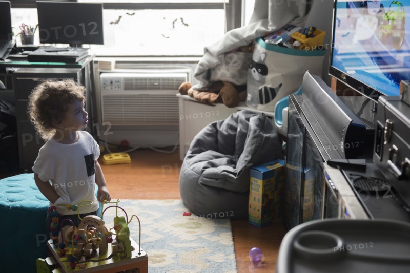Caucasian boy playing in livingroom with toys and watching television