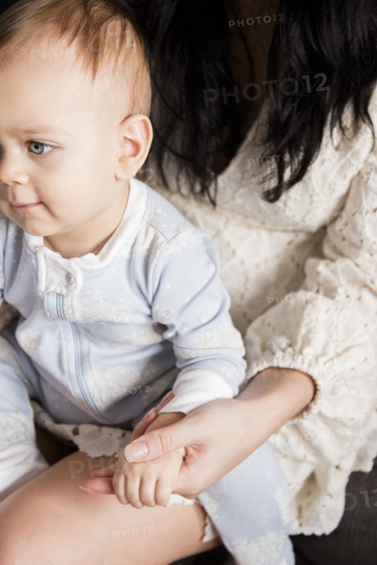 Caucasian baby boy sitting in lap of mother