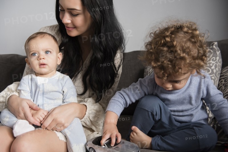Caucasian mother sitting on sofa with sons