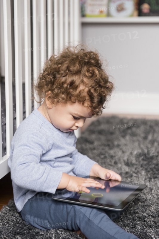 Caucasian boy sitting on floor playing with digital tablet