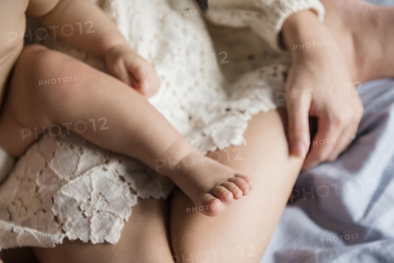 Leg of Caucasian baby boy sitting on lap of mother