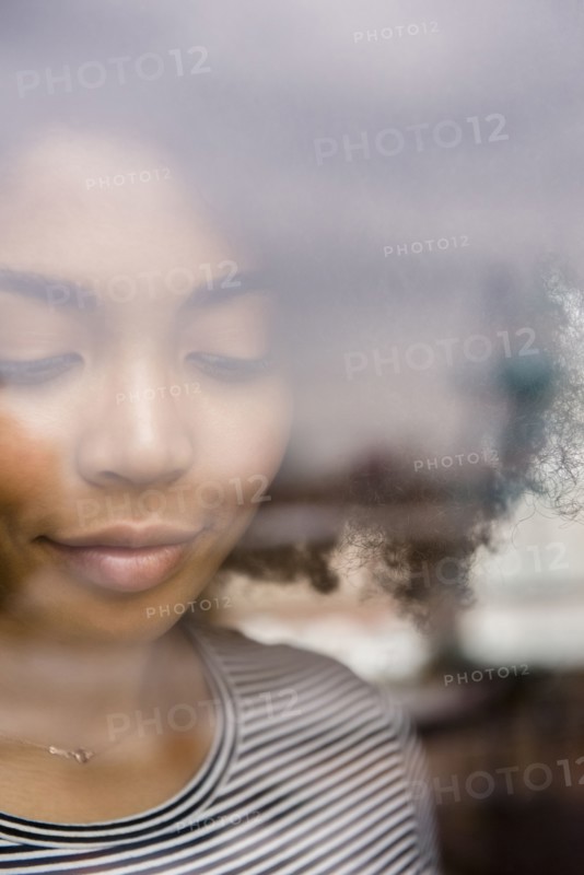 Pensive African American woman behind window