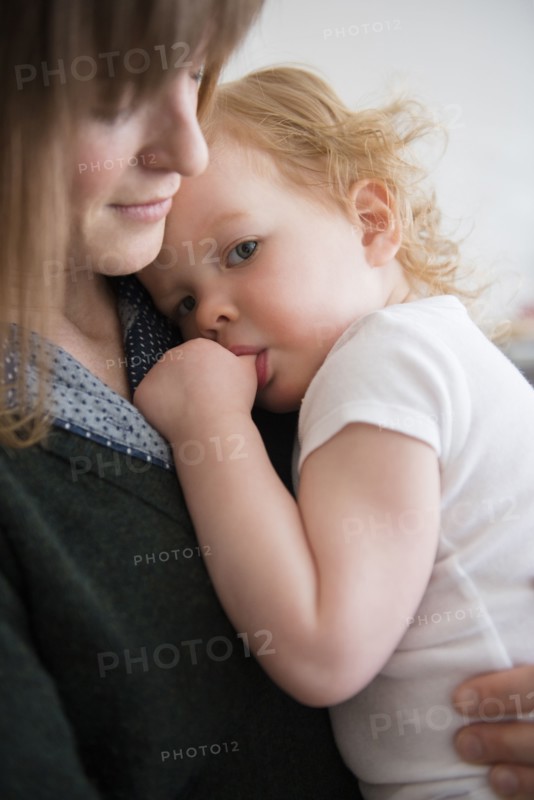 Caucasian mother holding daughter sucking thumb