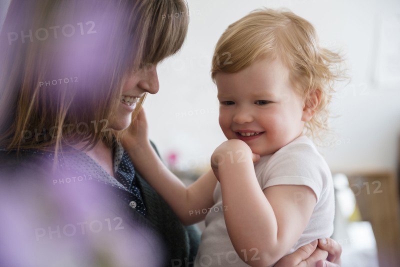 Caucasian mother holding laughing daughter