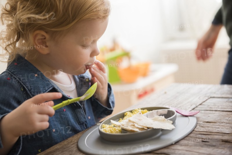 Caucasian girl eating with fingers and spoon