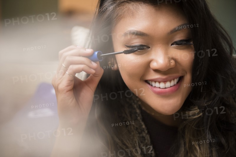 Mixed Race woman applying mascara
