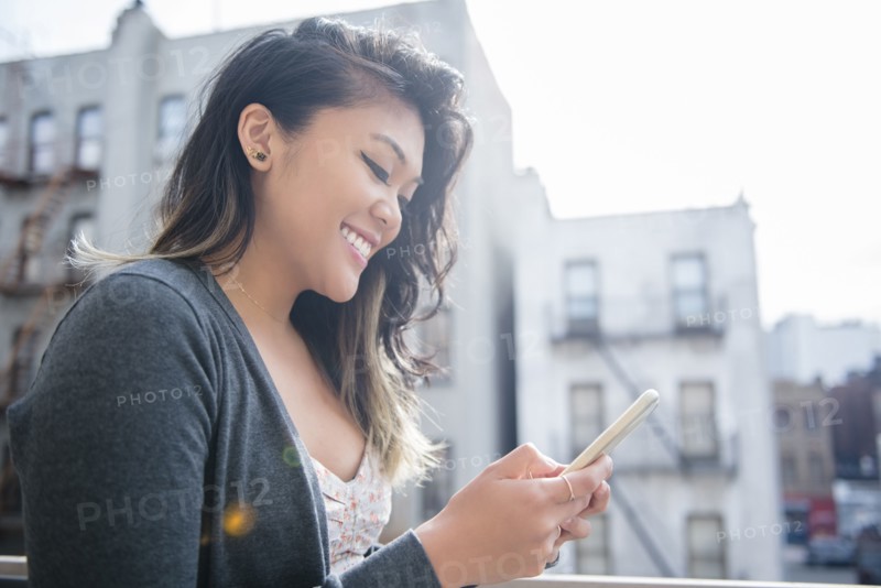 Mixed Race woman texting on cell phone in city