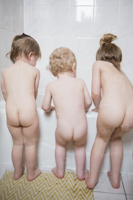 Naked Caucasian boy and girls standing near bathtub