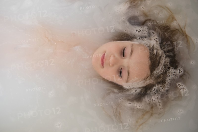 Face of Caucasian girl floating in bubble bath