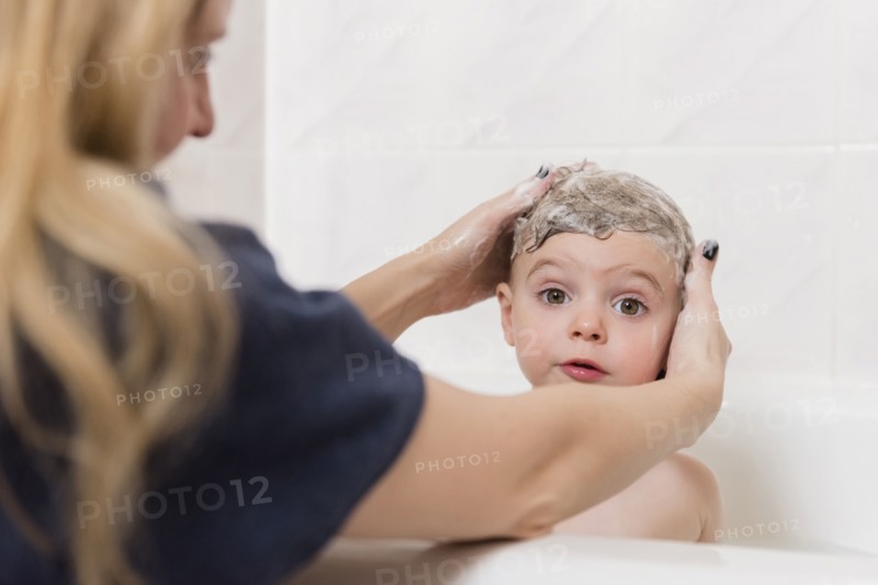 Caucasian mother washing hair of girl in bathtub