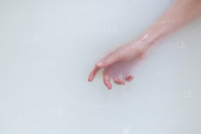 Hand of Caucasian woman in the milk bath