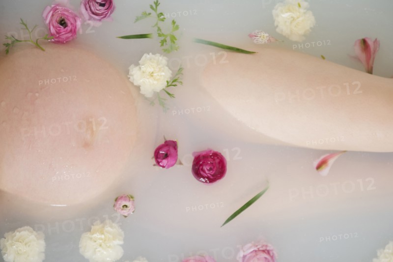 Caucasian expectant mother in milk bath with flowers