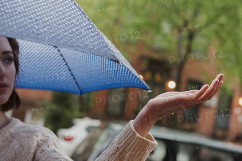 Caucasian woman holding umbrella checking rain