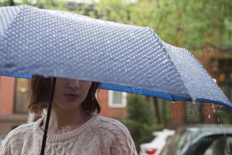 Caucasian woman holding an umbrella in rain