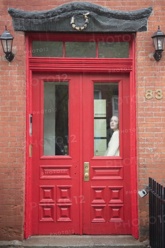 Caucasian woman daydreaming behind red door