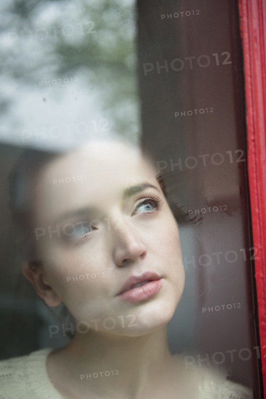 Caucasian woman daydreaming behind foggy window