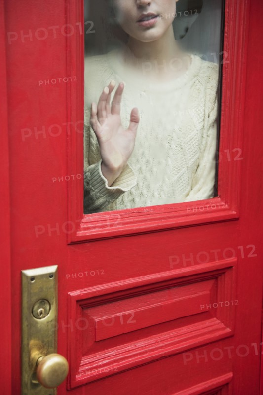 Caucasian woman daydreaming behind red door