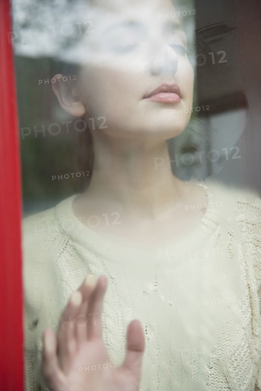 Caucasian woman daydreaming behind foggy window
