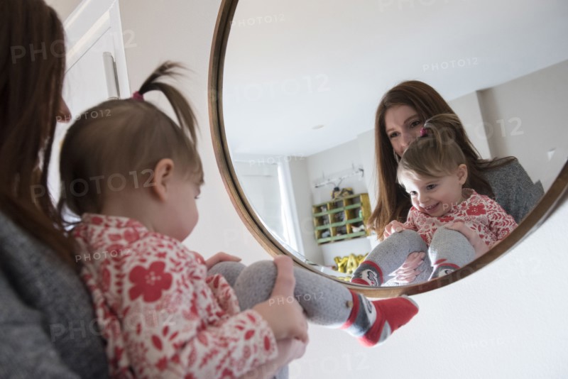 Reflection of Caucasian mother and baby daughter in mirror