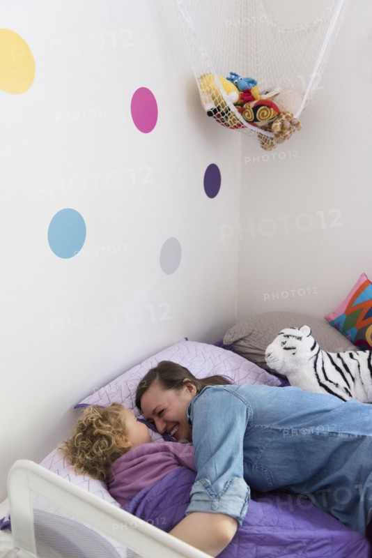 Caucasian mother and daughter laughing and cuddling in bed