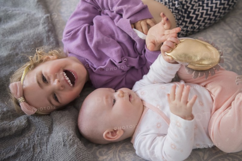 Caucasian girl laying on floor with baby sister