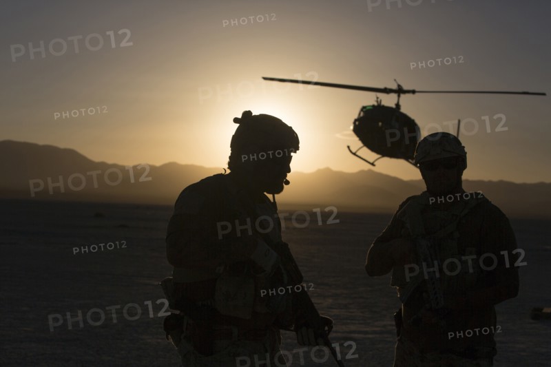 Silhouette of soldiers and helicopter in desert landscape