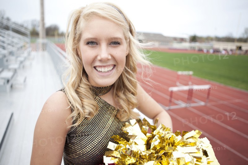 Caucasian cheerleader smiling on bleachers