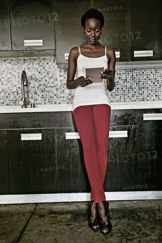 Black woman using digital tablet in kitchen