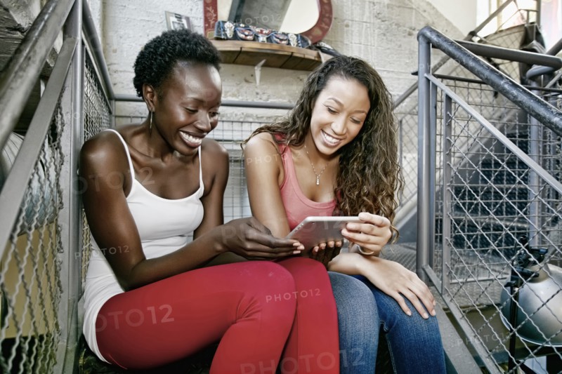 Women using digital tablet on steps