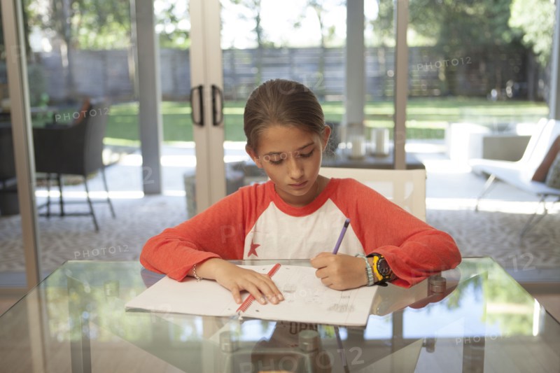 Mixed race girl doing homework at table