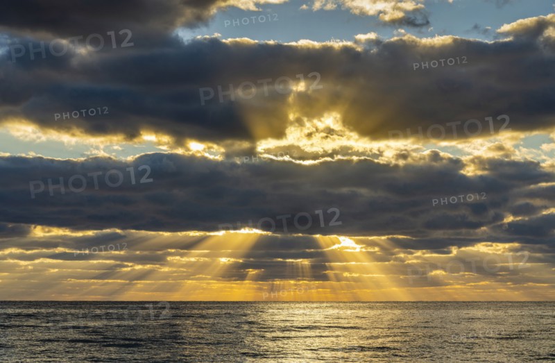 Sunrays and golden clouds over ocean at sunrise