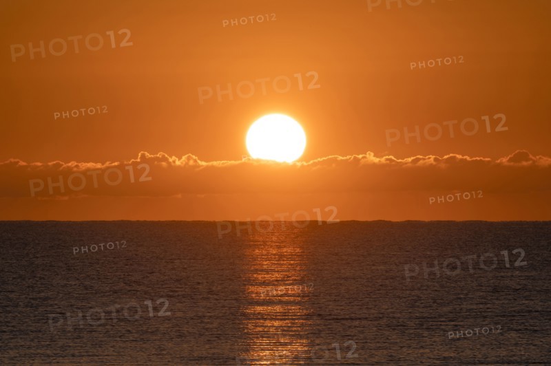 Blazing sunrise in orange sky over ocean