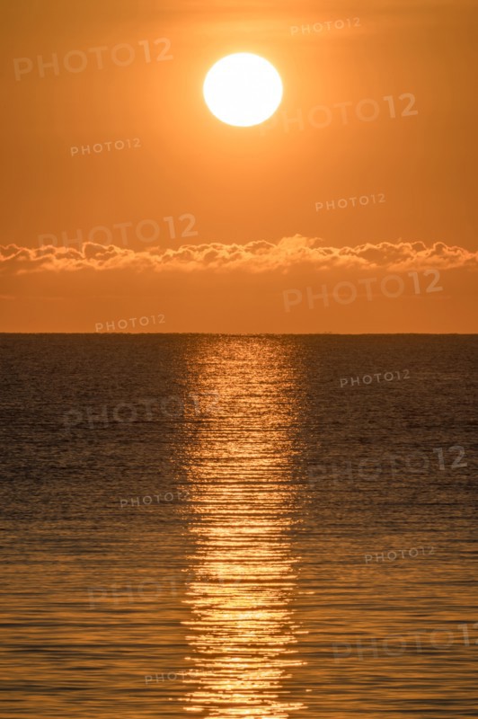 Blazing sunrise in orange sky over ocean