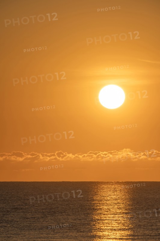 Blazing sunrise in orange sky over ocean