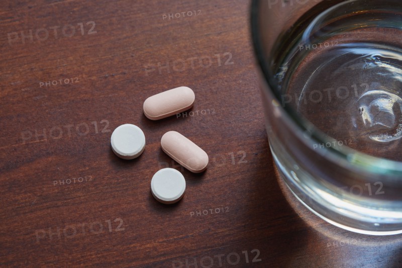 Overhead view of glass of water and pills on table