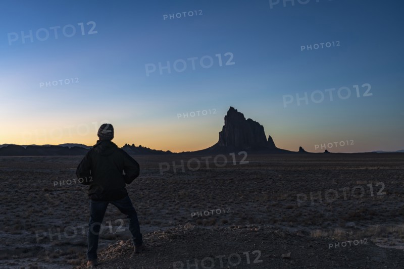 Silhouette of man looking at Ship Rock at sunset