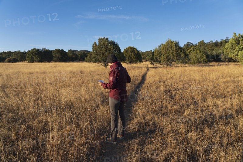 Woman o footpath crossing grassy field looking at map