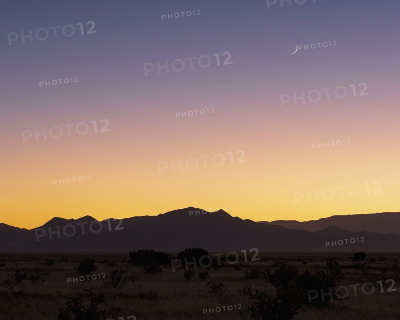Crescent moon above Jemez Mountains at sunset