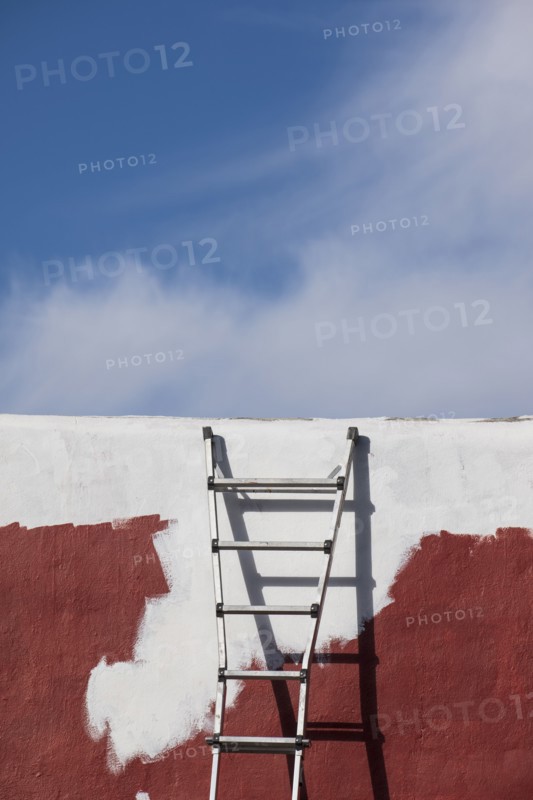 Ladder against partially painted brown and white wall