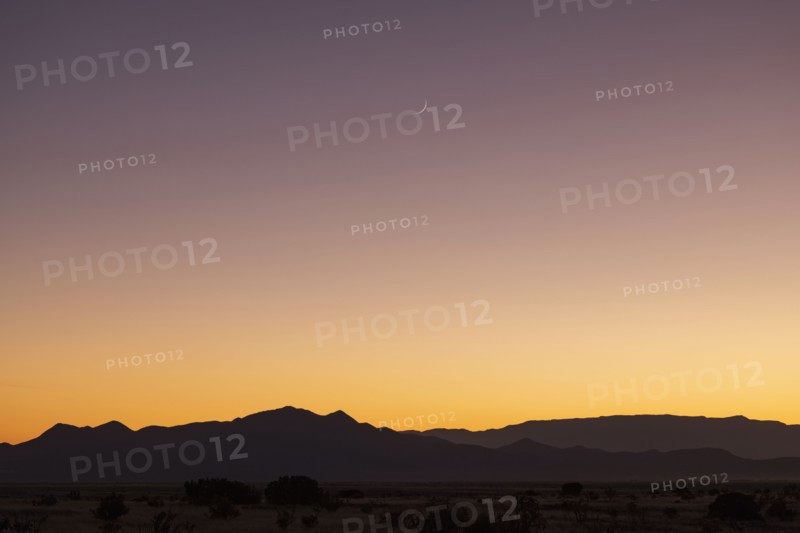 Crescent moon above Jemez Mountains at sunset