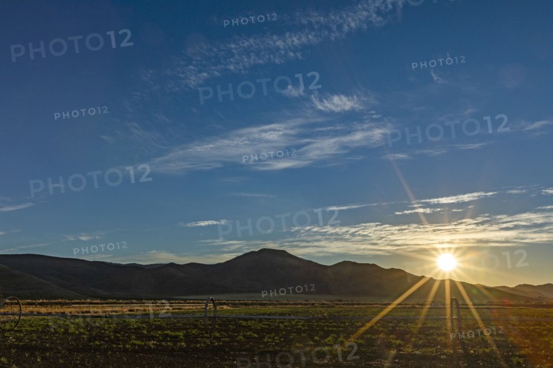 Sun rising over fields and hills
