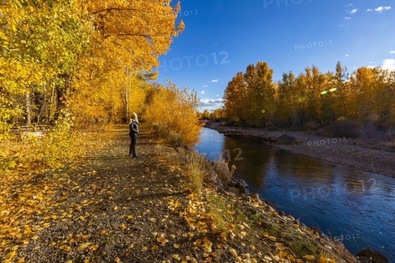 Senior woman walking along Big Wood river in Autumn