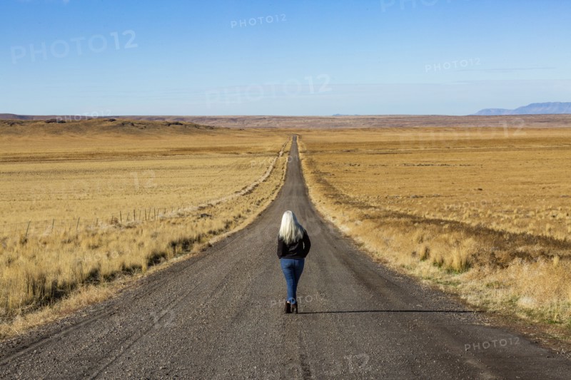 Senior woman walking down desert road
