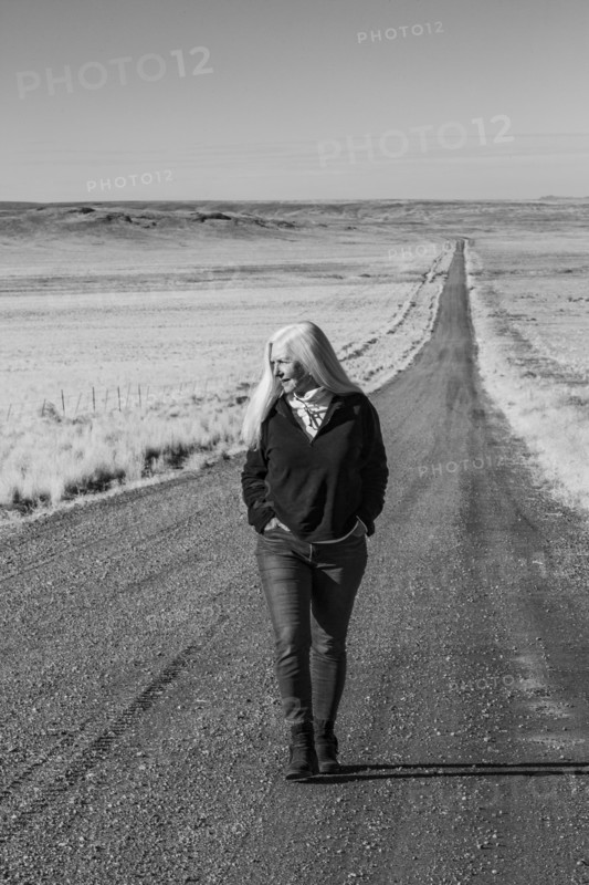 Senior woman walking down desert road