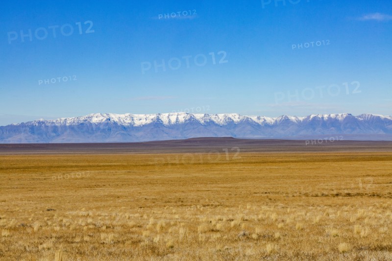Desert and distant mountains under blue sky